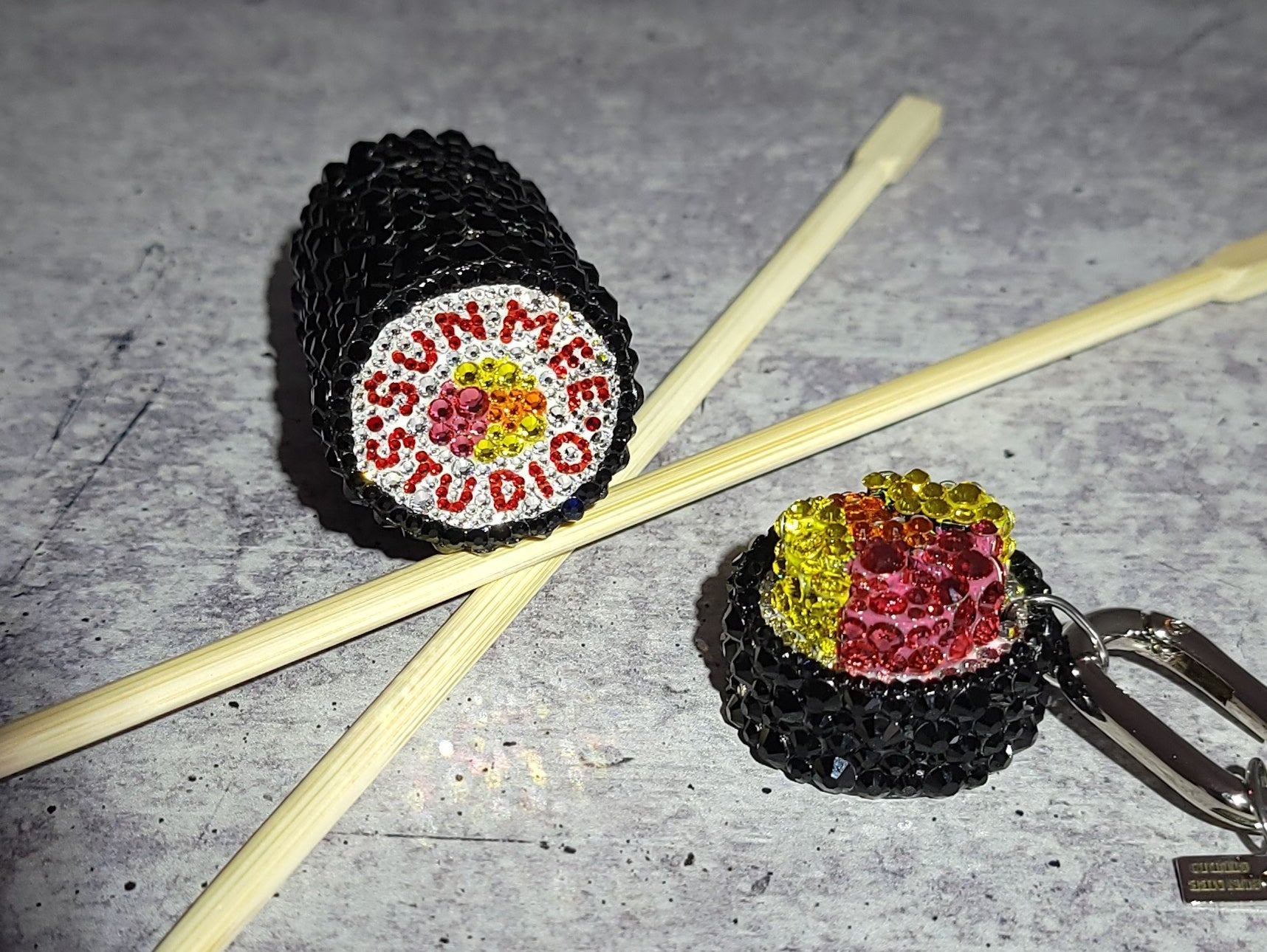 SNACK GIMBAP Keychain show with the top twisted off to demonstrate the screw off portion of the keychain, and showing the bottom of the keychain which features a hand painted motif.